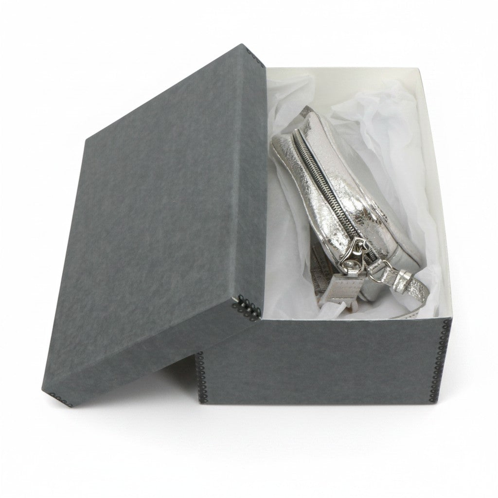 Kept Store acid-free grey storage box protecting a small metallic silver crossbody handbag with white tissue paper.
