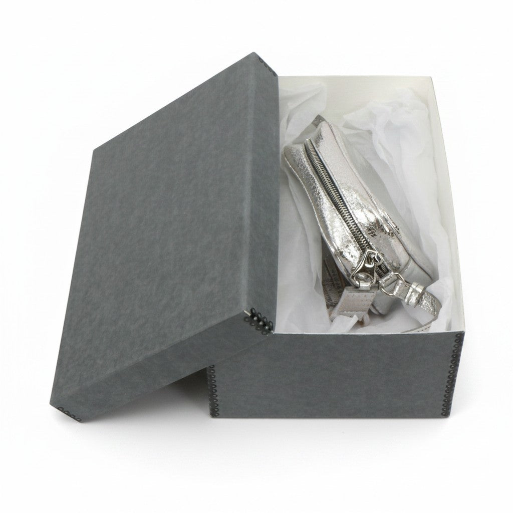 Kept Store acid-free grey storage box protecting a small silver crossbody handbag with white tissue paper.